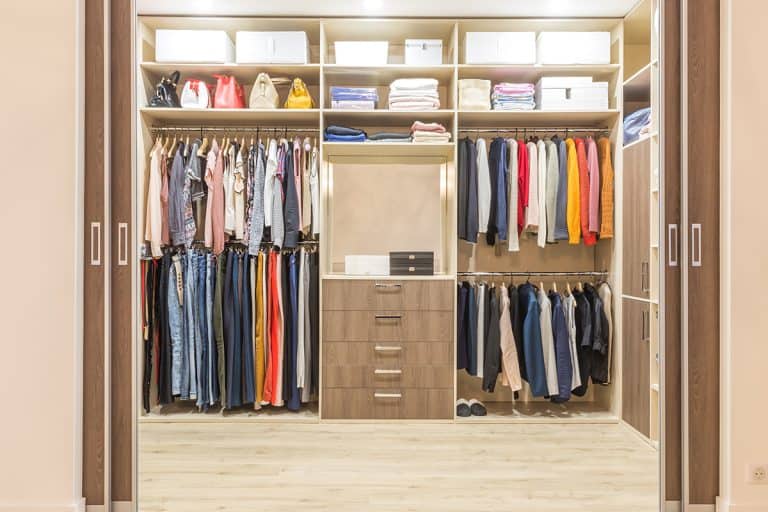 Modern wooden wardrobe with clothes hanging on rail in walk in closet, Closet Fusion: The Ultimate Guide to Combining Two Closets into One