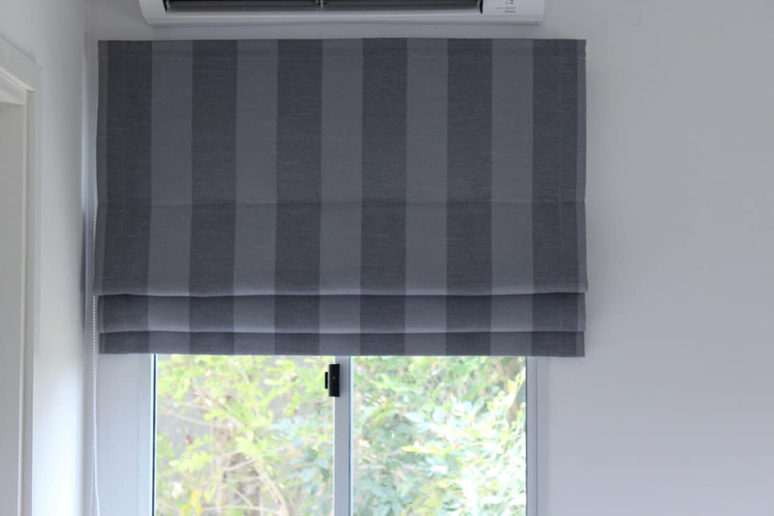 Grey roman blind with strip pattern on the window.
