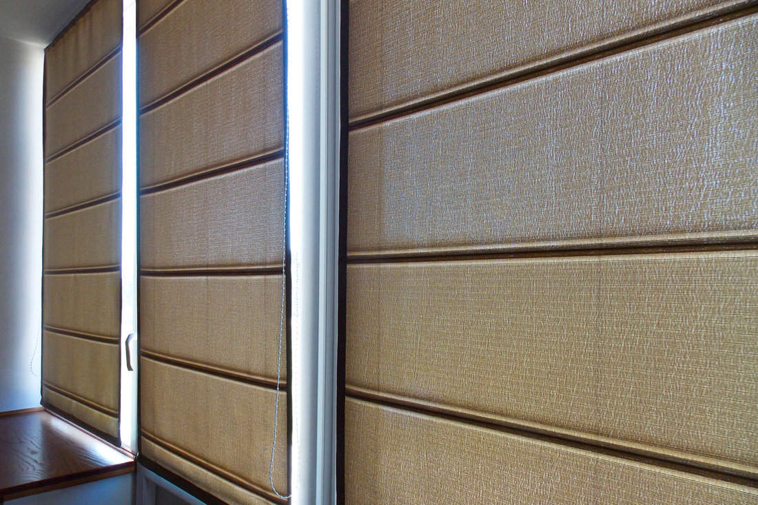 Roman blinds brown color on the window closeup in the interior
