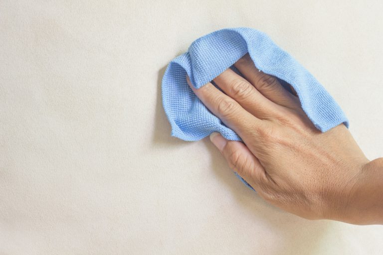 hand cleaning a wall using a microfiber cloth