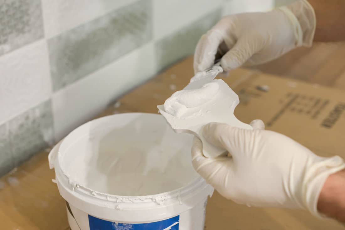 Close-up of hands rubbing interlayer tabs with putty epoxy grout