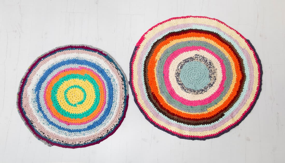 Colorful crochet rug from repurposed T-shirts at white wooden home floor.