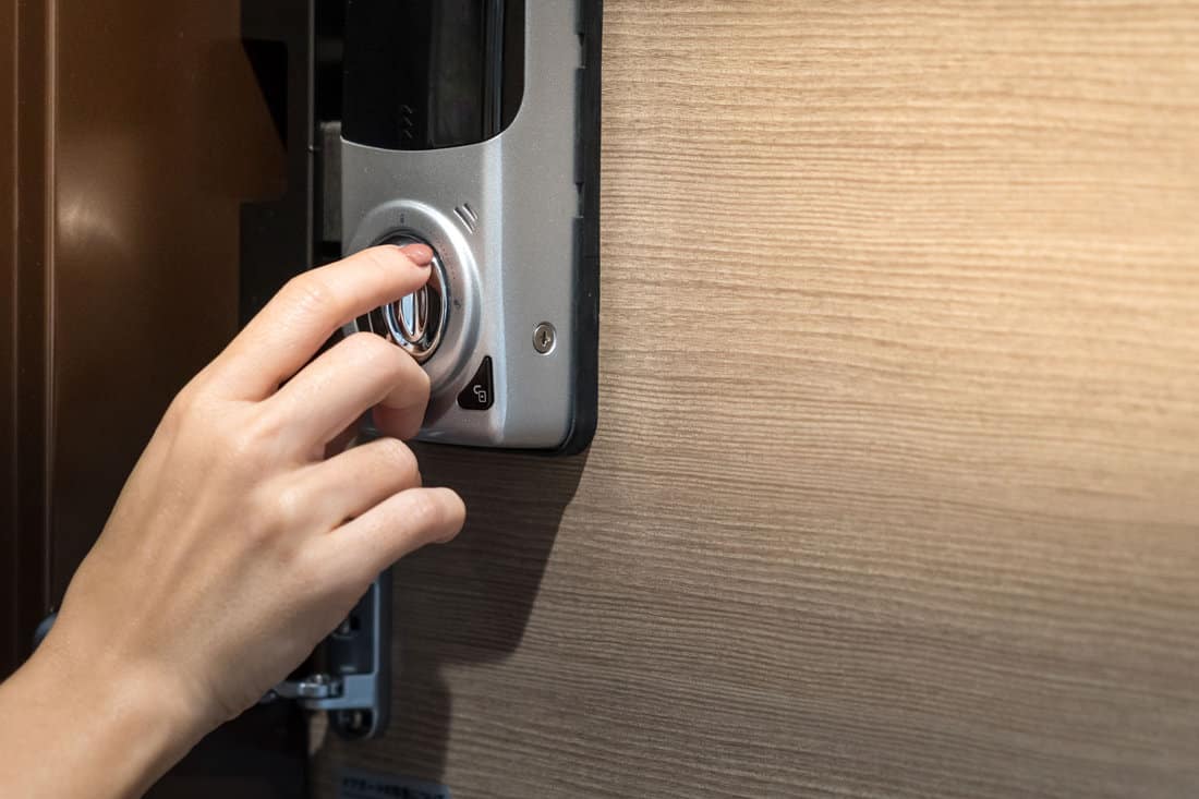 A close-up view of the hands of a lovely woman turning the Wyze door sensor lock to unlock the door from inside a hotel or apartment room. This keyless, intelligent safety home system offers an emergency unlock activation feature.