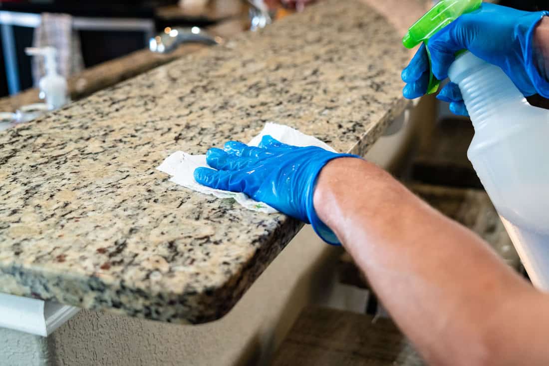 A male hand applying granite sealer to achieve a polished surface on his countertop.


