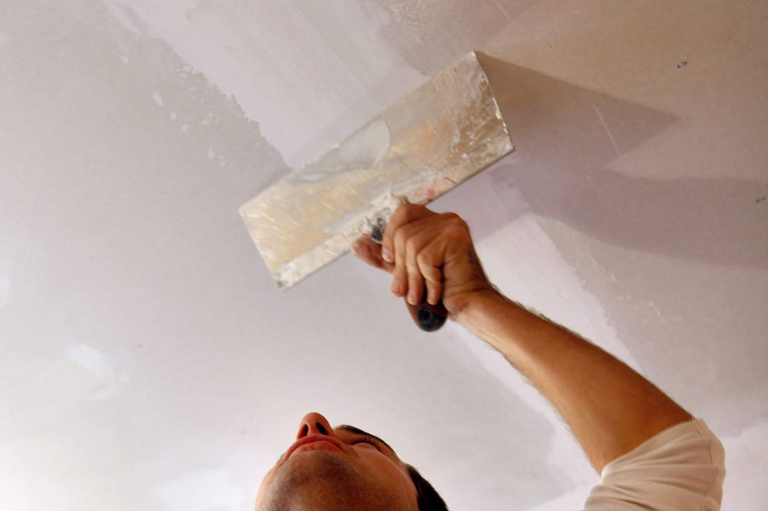 A man applying mud to the ceiling.

