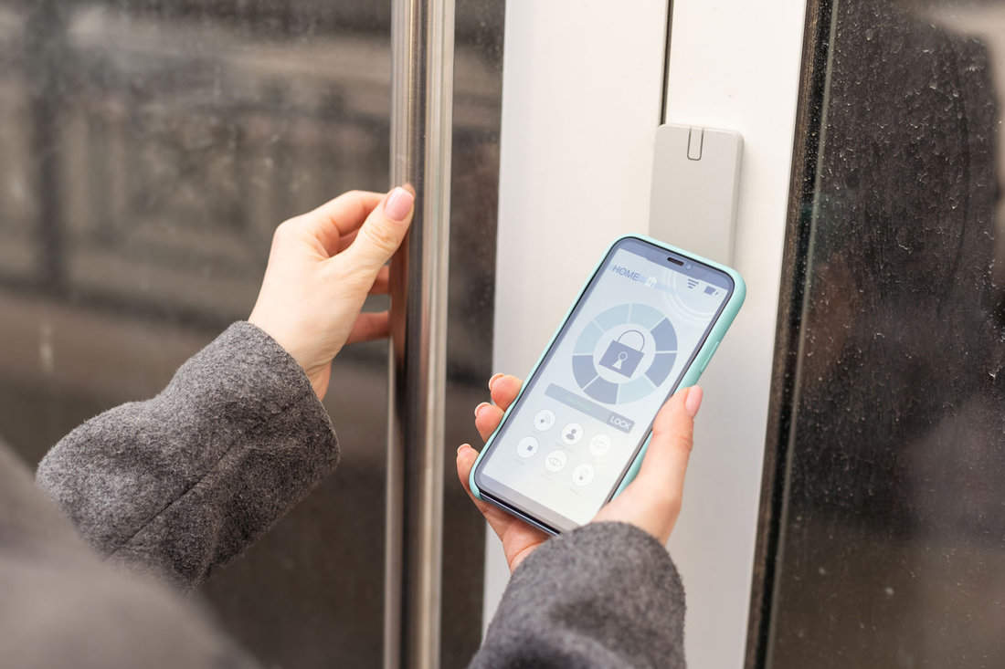A woman secures a smartlock on the entrance door using her smartphone, embodying the concept of utilizing smart electronic locks for keyless access.

