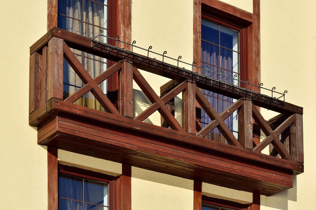 A charming wooden French balcony graces the new house's wall. The intricate crisscross porch railing adds to its allure, combining safety with aesthetics seamlessly.