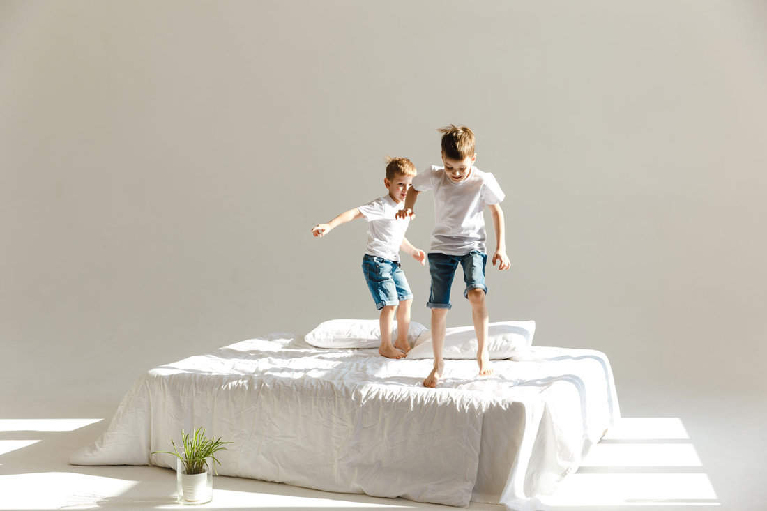 Engaging in a positive indoor activity, young children are joyfully jumping on a purple mattress.