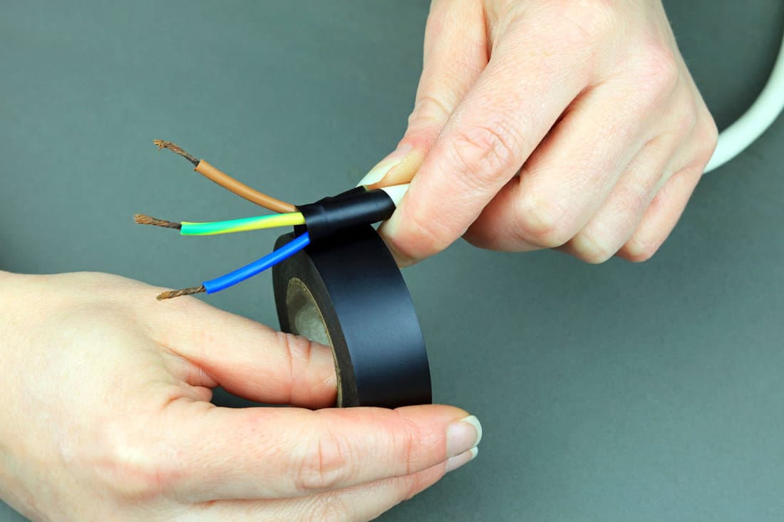 Hands Applying Electrical Insulation Tape To Electrical Cable.
