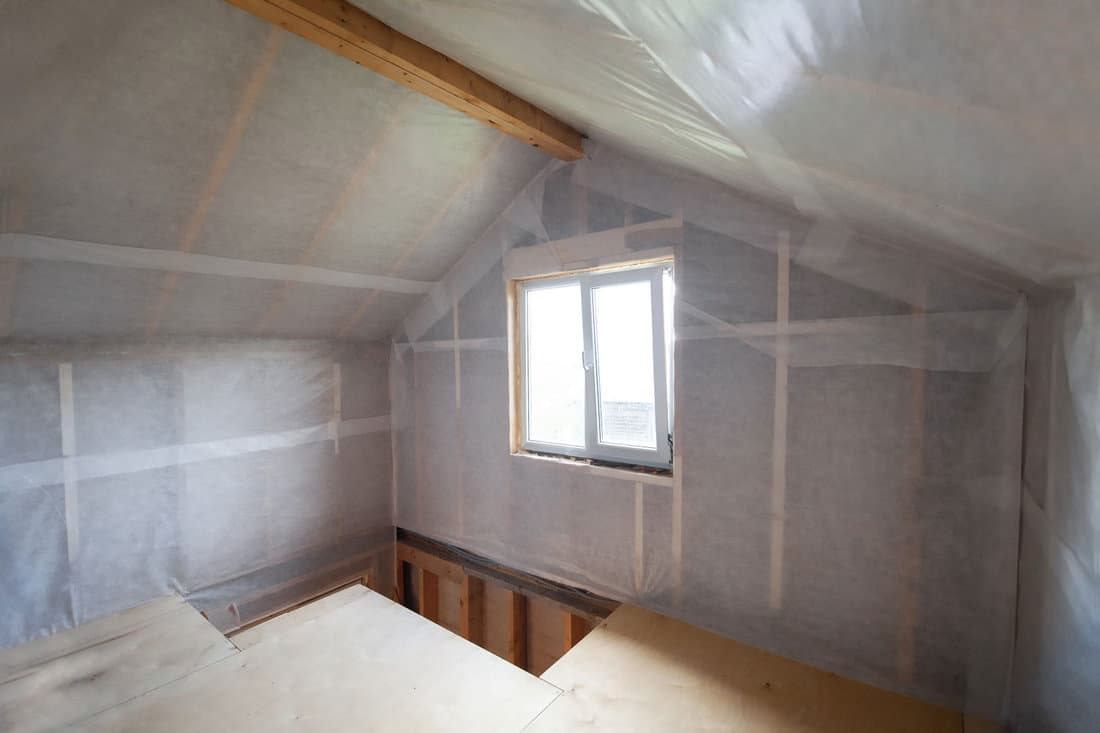 A vapor barrier membrane, in the form of Tyvek home wrap, covers the walls of the framed house.
