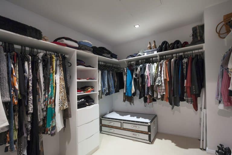 Interior of a modern walk-in closet filled with lots of cloths and bags