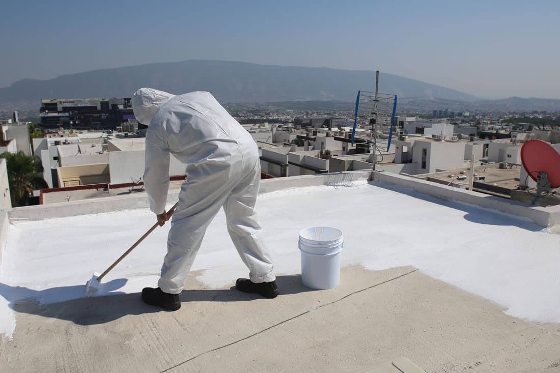 Worker applying elastomeric coating on the roof