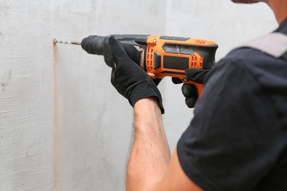 Worker using a drill to make a hall in the wall
