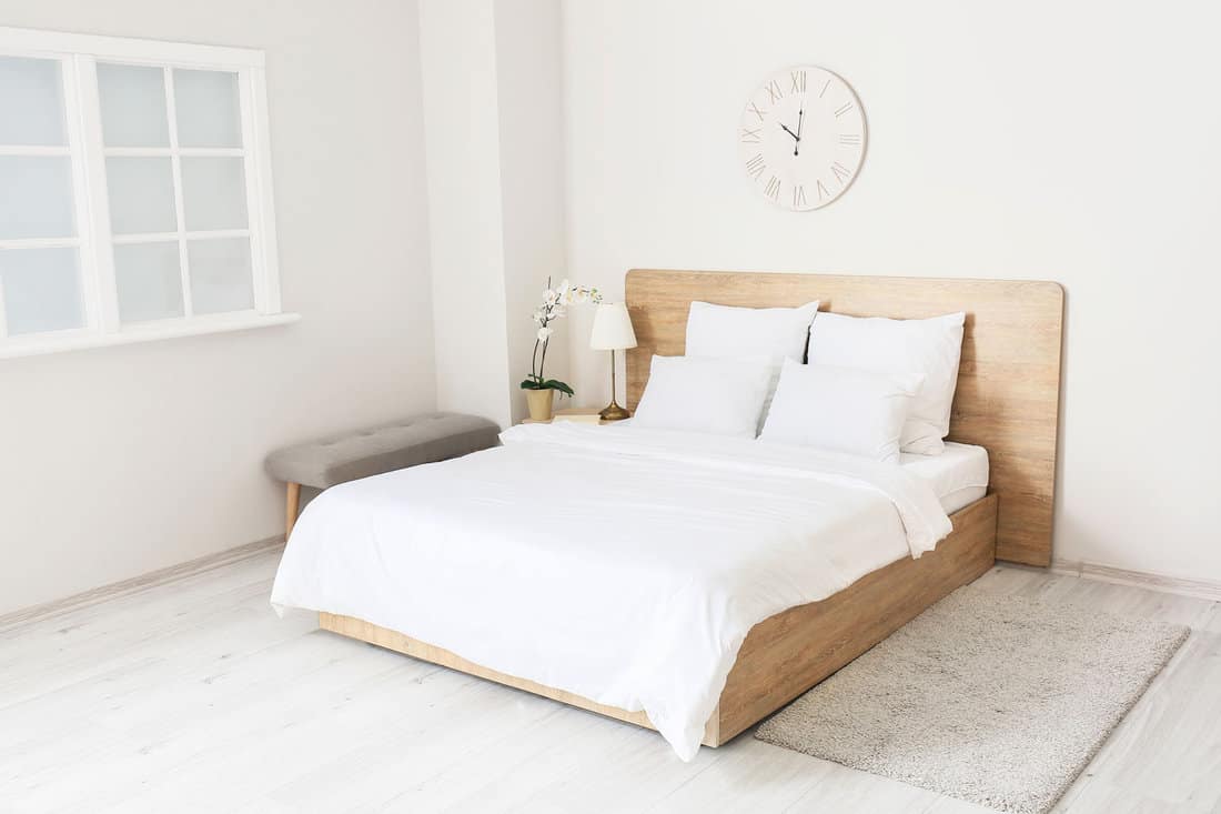 White themed bedroom with matching white beddings and wooden  bed