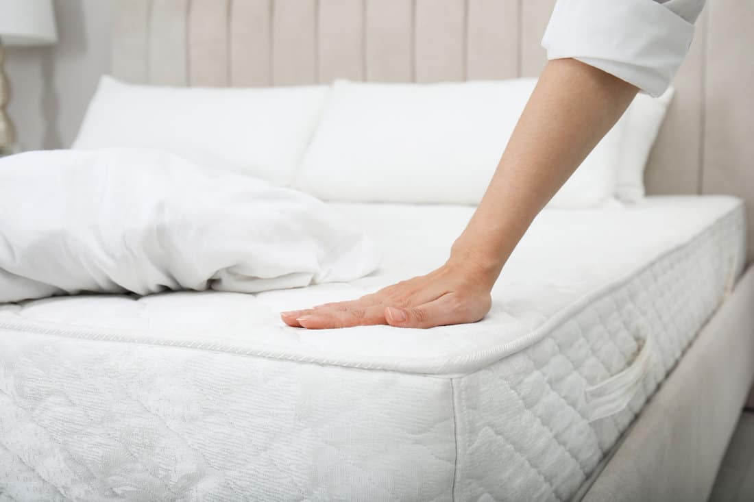 woman feeling the mattress in the bedroom