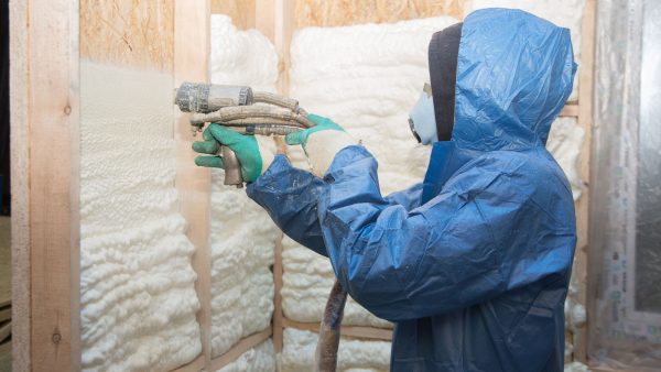 Worker spraying foam insulation to the wall - 1600x900