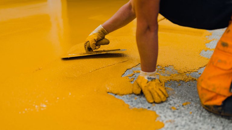 Worker spreading epoxy on the floor, How To Use Quikrete Epoxy Concrete Repair - 1600x900
