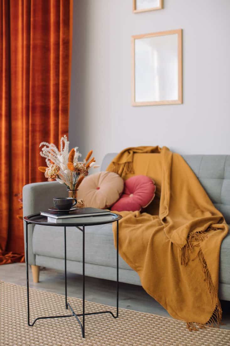 Cozy living space with amber drapes and mustard throw.