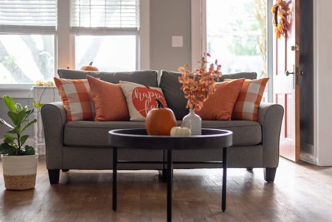 Fall-themed living room with orange cushions and pumpkins.