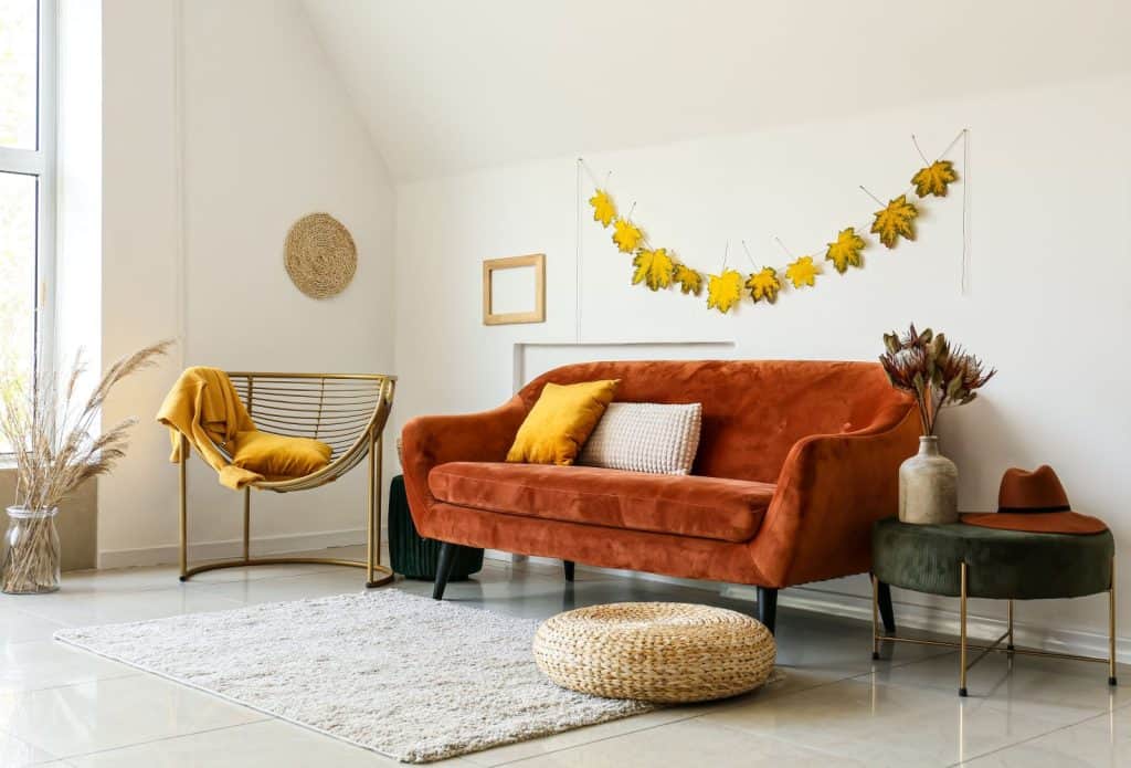 Boho living room with rust sofa and golden chair. Fall decor motifs