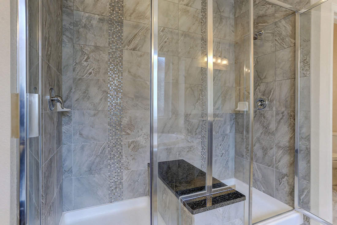 Modern bathroom interior with glass shower wall and a shower bench