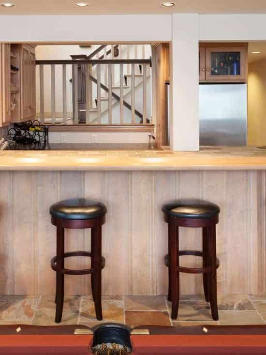 A small bar under a rustic basement with rustic bar stools arranged near the table