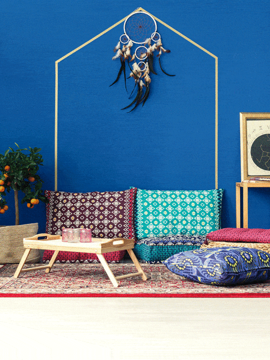 Oriental interior with colorful pattern pillows, blue wall, plants, and rug