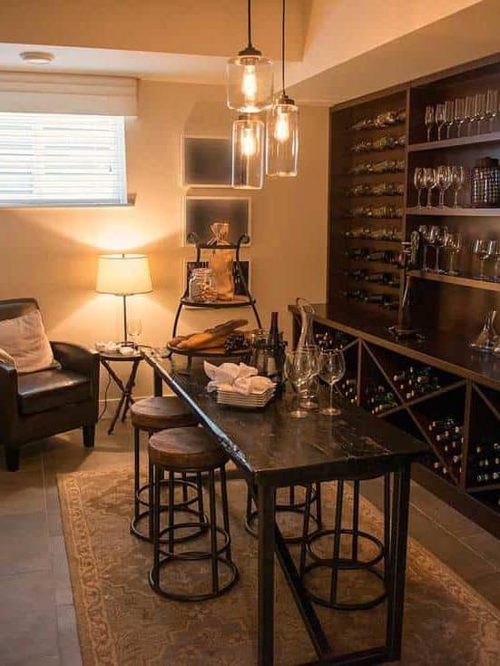 Rustic basement interior with dark dining furniture and wine filled shelves