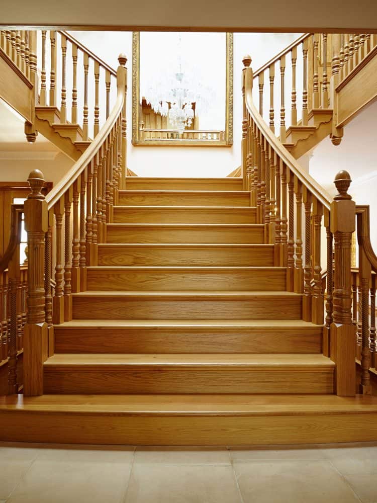 A curved oak staircase with wooden banisters and a light gray tiled flooring