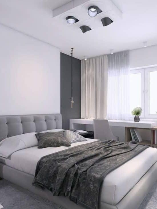 A gray and white themed bedroom with a white bed and a gray blanket with a shelf