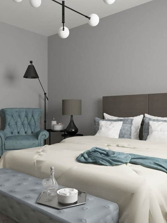 A gray bedroom with brown shelves on the side and an off white blanket