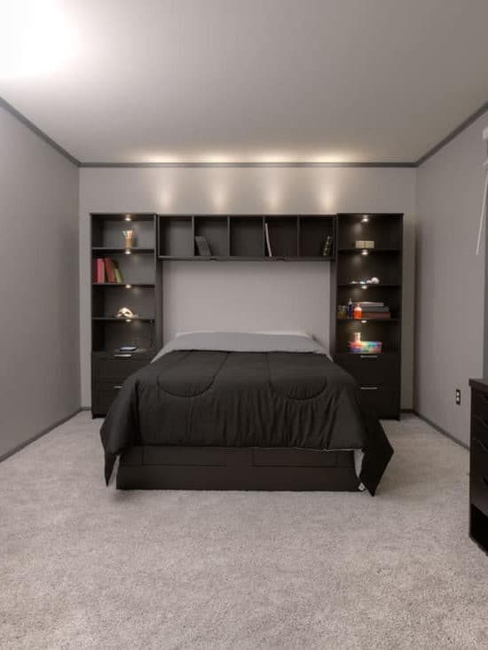 A gray colored living room with a black furnitures and appliances and a black bed with a black bedding sets