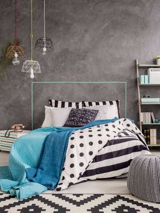 An industrial themed bedroom with a gray wall and stripped rug