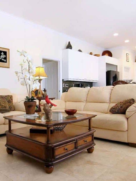 Beautiful classic family room with cozy sofa, wooden table, tiled floor and white wall