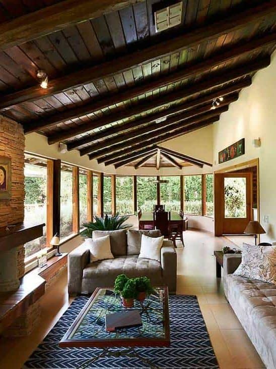 Classic rustic living room interior design with fireplace, sofa set, tiled floors and glass windows