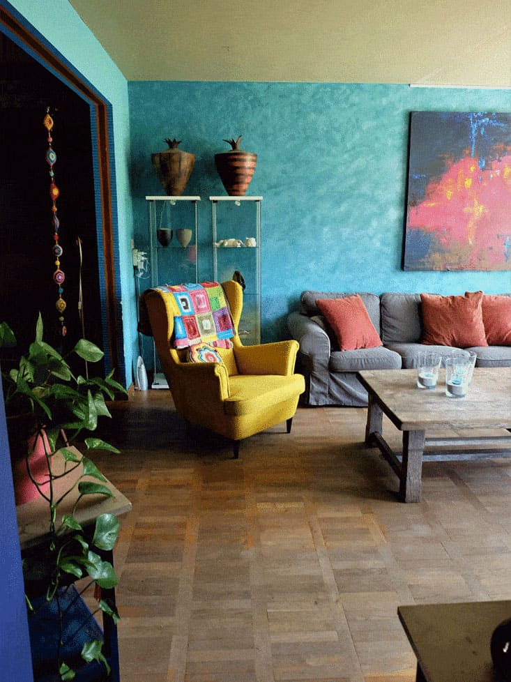 A boho-inspired living room featuring a yellow armchair, eclectic wall colors and vintage pieces.